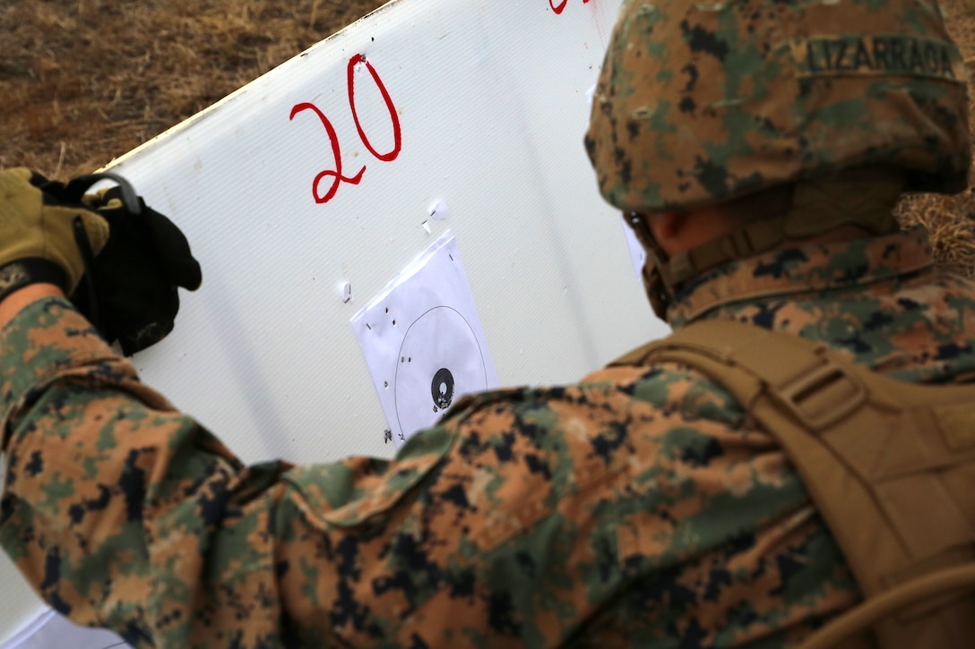 Cpl. Steve Lizarraga, rifleman, 1st Platoon, Company A, Ground Combat Element Integrated Task Force, examines the initial shot groups of Lance Cpl. Anne Creasy, rifleman, 2nd Platoon, Co. A, GCEITF, during the M27 Infantry Automatic Rifle 100-meter zeroing course of fire during a three-day field exercise at the Verona Loop training area on Marine Corps Base Camp Lejeune, North Carolina, Dec. 3, 2014. (U.S. Marine Corps photo by Sgt. Alicia R. Leaders/Released)