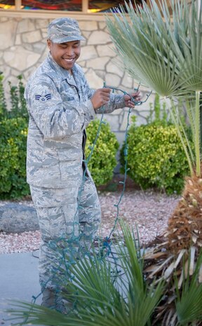 Senior Airman Alvin De Leon, 99th Civil Engineer Squadron high-voltage electrician, untangles a strand of holiday lights to wrap around a plant near the base chapel on Nellis Air Force Base, Nev., Nov. 25, 2014. The annual base tree lighting ceremony is scheduled to take place at the chapel parking lot Dec. 4. (U.S. Air Force photo by Airman 1st Class Mikaley Towle)