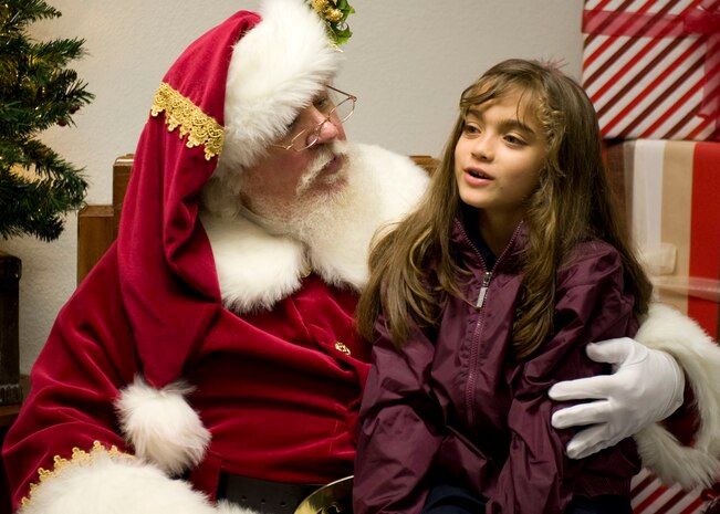 Andrea, 8, sits with Santa Claus and tells him what she wants for Christmas inside the chapel at Nellis Air Force Base, Nev., Dec. 4, 2014. Airmen and their families met in the  chapel parking lot to sing carols, eat food and meet with Santa during the holiday tree and menorah lighting ceremony. (U.S. Air Force photo by Airman 1st Class Mikaley Towle)