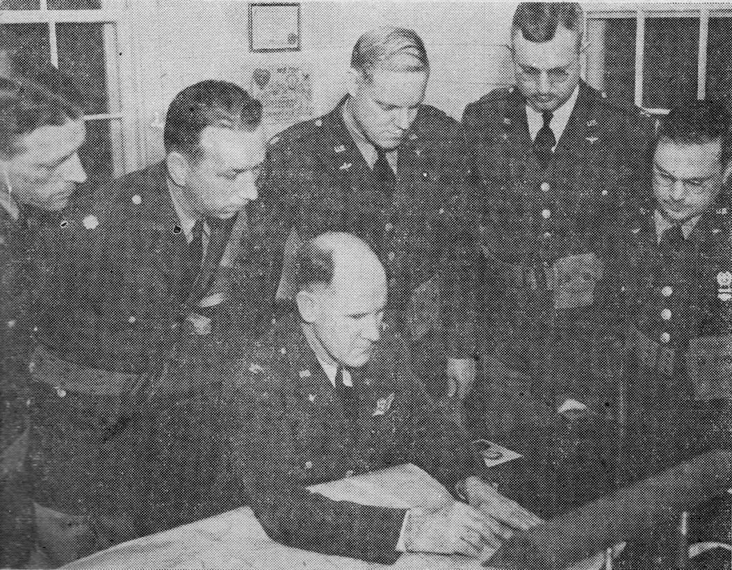 Col Stromme, Commander of Portland AAB, seated, and his staff read the declaration of war after the Japanese attack in the Pacific.  Standing behind him, left to right, are Captain Herbert S. Beeks, Commander, 43rd ABG, Major Milton W. Kingcaid, base executive officer, Major Glen G. Heavenridge, Commander, HQ and HQ Squadron, Captain Walter W. Robinson, Base S-1 and Captain Alexander Cohn, Supply Officer.  Note the standing officers in service dress uniforms, with M-1936 pistol belts and .45 caliber automatic pistol ammunition pouches.  (142FW History Archives)