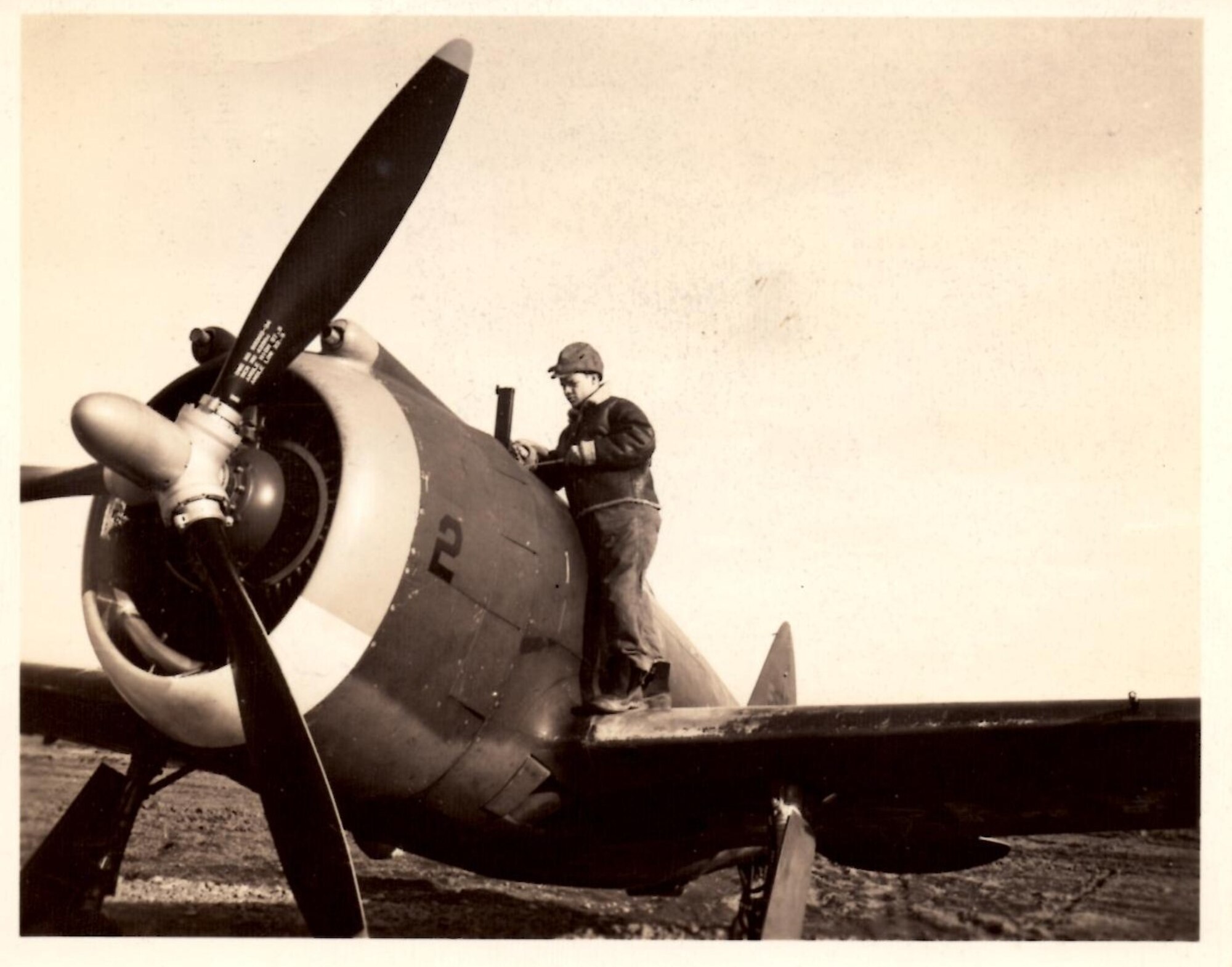 Republic P-43 Lancer of the 55th Pursuit Group being serviced at Portland AAB in this undated photograph.  The enlisted man servicing the aircraft may be an armorer working on the .50 caliber machine gun.  Note the multi-colored leading edge of the engine cowling and the low number “2” on the cowling, suggesting a ship flown by a pilot on group staff with colors representing the three assigned pursuit squadrons.  (142FW History Archives, Robert Hall Collection)