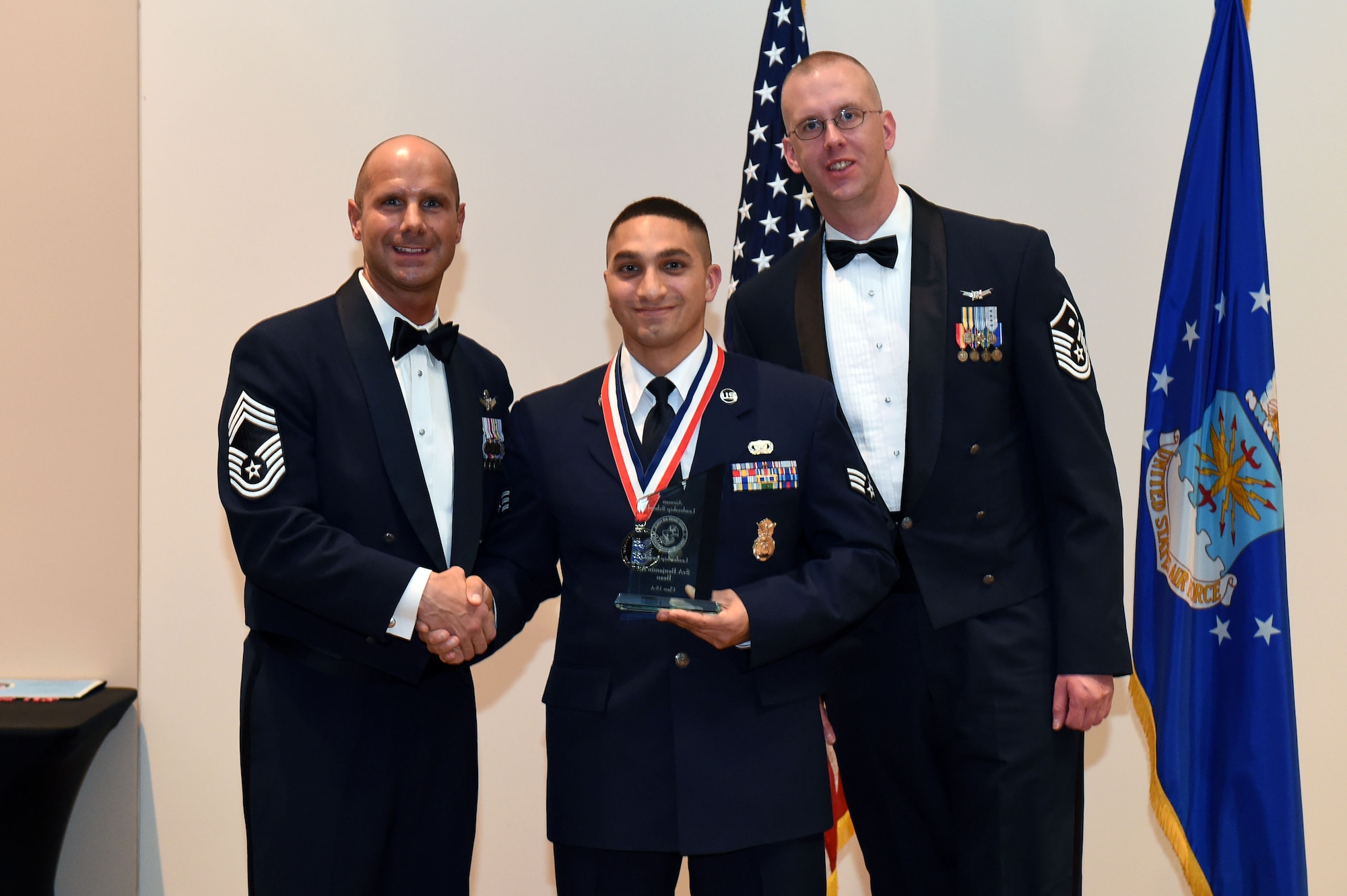 Senior Airman Benjamin Del Valle, 460th Security Forces Squadron, center, receives the Leadership Award during the Buckley Airman Leadership School Class 15-A graduation Dec. 4, 2014, at the Leadership Development Center on Buckley Air Force Base, Colo. This award is presented to the graduate who displays the best overall characteristics of an effective leader. (U.S. Air Force photo by Airman 1st Class Emily E. Amyotte/Released)