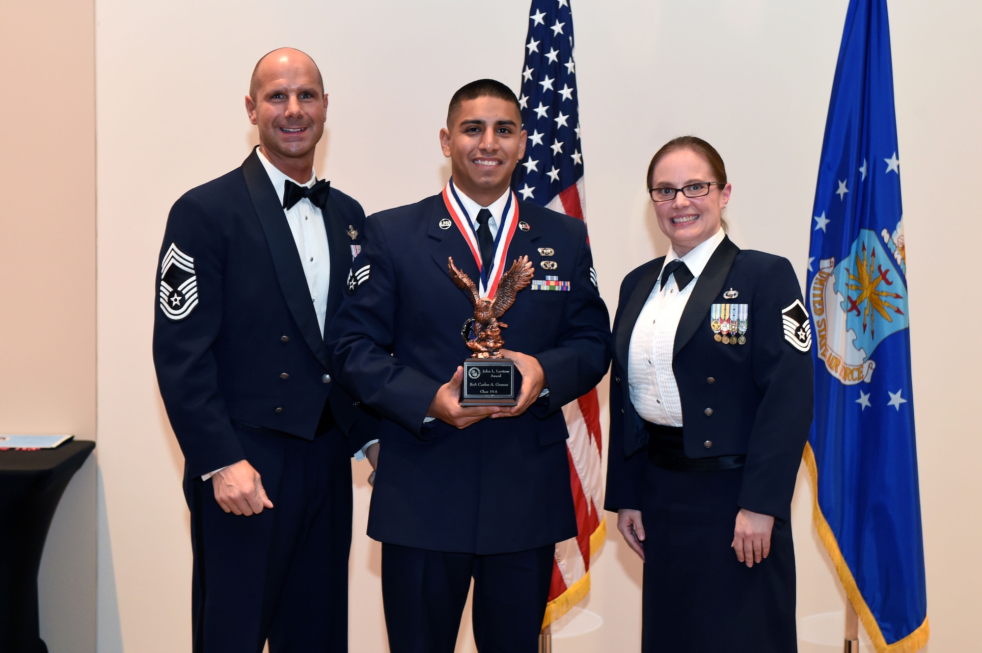 Senior Airman Carlos Gomez, 460th Civil Engineer Squadron, center, receives the John L. Levitow Award during the Buckley Airman Leadership School Class 15-A graduation Dec. 4, 2014, at the Leadership Development Center on Buckley Air Force Base, Colo. The Levitow award is given to the ALS graduate with the highest academic scores and leadership potential. (U.S. Air Force photo by Airman 1st Class Emily E. Amyotte/Released)