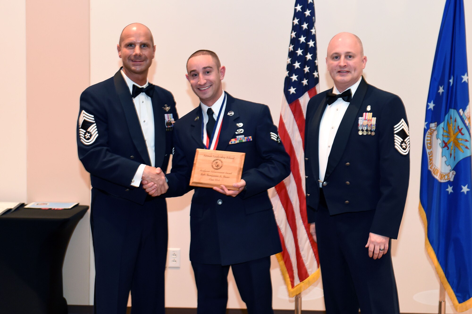 Senior Airman Benjamin Bean, 460th Civil Engineer Squadron, center, receives the Academic Achievement Award during the Buckley Airman Leadership School Class 15-A graduation Dec. 4, 2014, at the Leadership Development Center on Buckley Air Force Base, Colo. This award is presented to the student with the highest overall average on all academic evaluations during ALS. (U.S. Air Force photo by Airman 1st Class Emily A. Amyotte/Released)