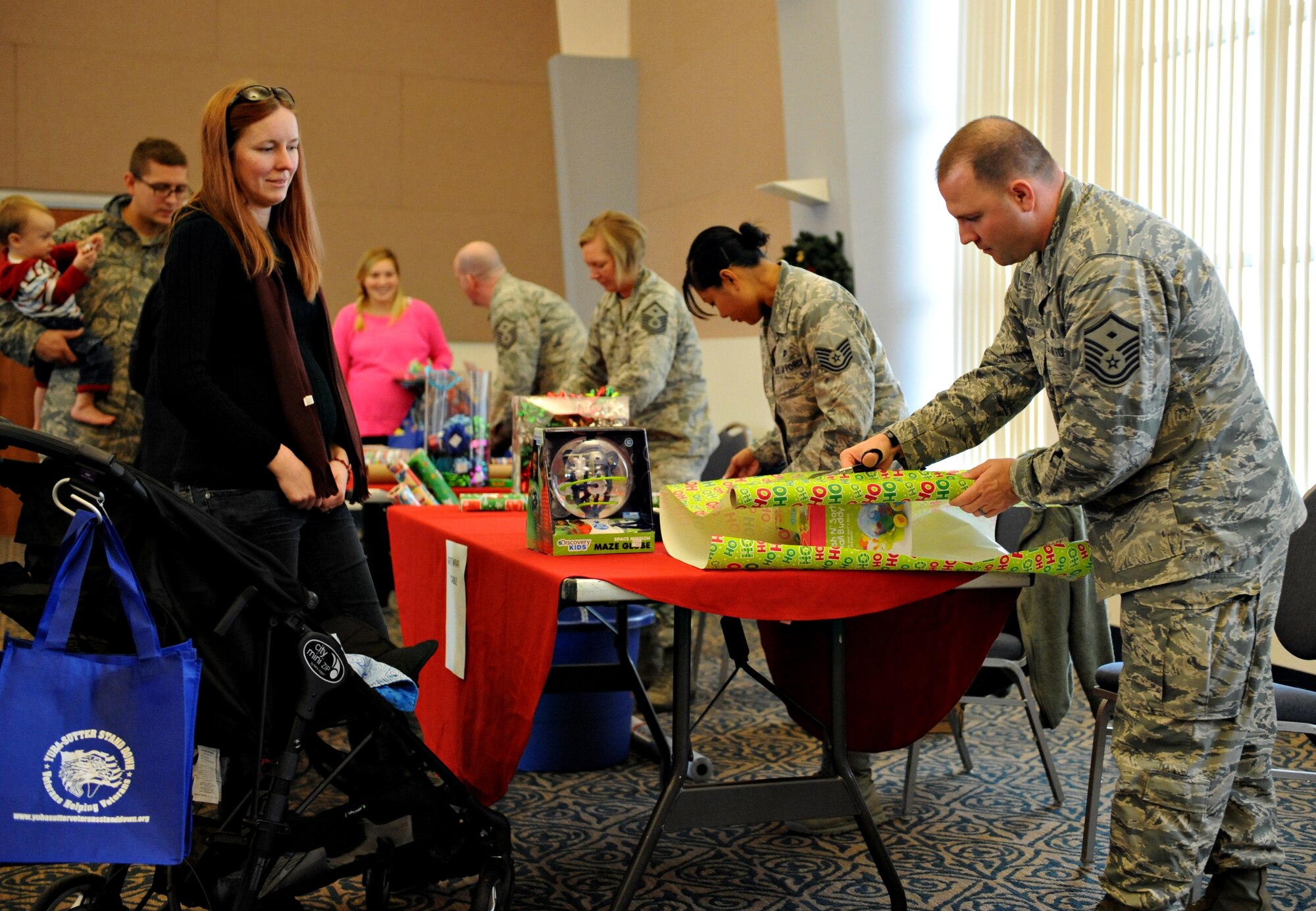 Team Beale’s first sergeants and other volunteers provides assistance with gift wrapping during Beale’s 2014 Holiday Toy Drive sponsored by Operation Homefront Dec. 4, 2014, at Beale Air Force Base, Calif. Operation Homefront is an organization, which provides many programs to assist military members with relief during difficult financial times, providing recovery for wounded warriors, and giving recognition to family members. (U.S. Air Force photo by Airman 1st Class Ramon A. Adelan/Released)