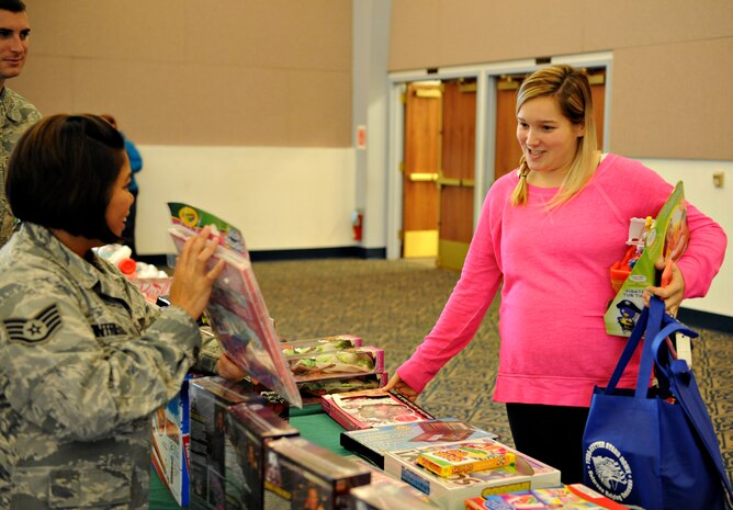 A volunteer for Beale’s 2014 Holiday Toy Drive, displays an assortment of gifts to Team Beale during the event, which was sponsored by Operation Homefront Dec. 4, 2014, at Beale Air Force Base, Calif. Operation Homefront is an organization, which provides many programs to assist military members with relief during difficult financial times, providing recovery for wounded warriors, and giving recognition to family members. (U.S. Air Force photo by Airman 1st Class Ramon A. Adelan/Released)