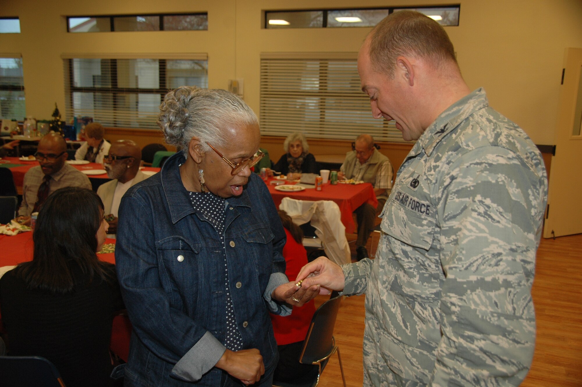Joan Kelley-Williams receives a commander’s coin in recognition of her 30 years of service to the American Red Cross from Col. George Dietrich, III, 60th Mission Support Group commander during the Travis Red Cross holiday luncheon for volunteers Wednesday at the First Street Chapel. Kelley-Williams steps down today as director of International and Services to the Armed Forces for the American Red Cross. (U.S. Air Force photo/Jim Spellman)