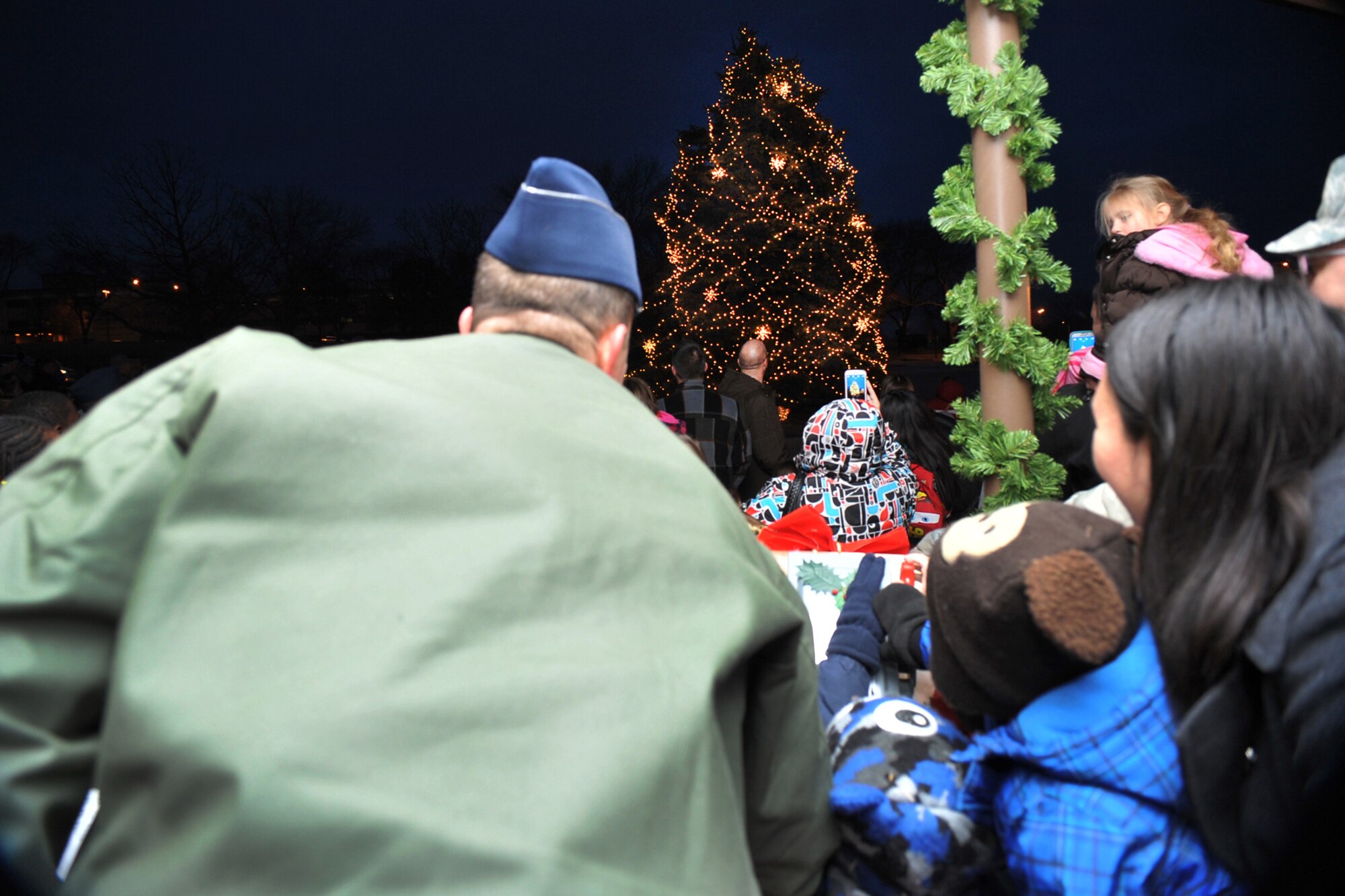 U.S. Air Force Brig Gen Gregory Guillot, 55th Wing commander, and the family of deployed U.S. Air Force Airman 1st Class Thomas Kugler, 55th Intelligence Squadron, turns on the lights during the annual Tree Lighting Ceremony held in front of the Patriot Club on Offutt AFB, Neb., Dec. 4. This annual event provides Team Offutt members and their families a fun environment to share their joy and give presents to their love ones this Christmas season. (U.S. Air Force photo by Charles Haymond/Released)