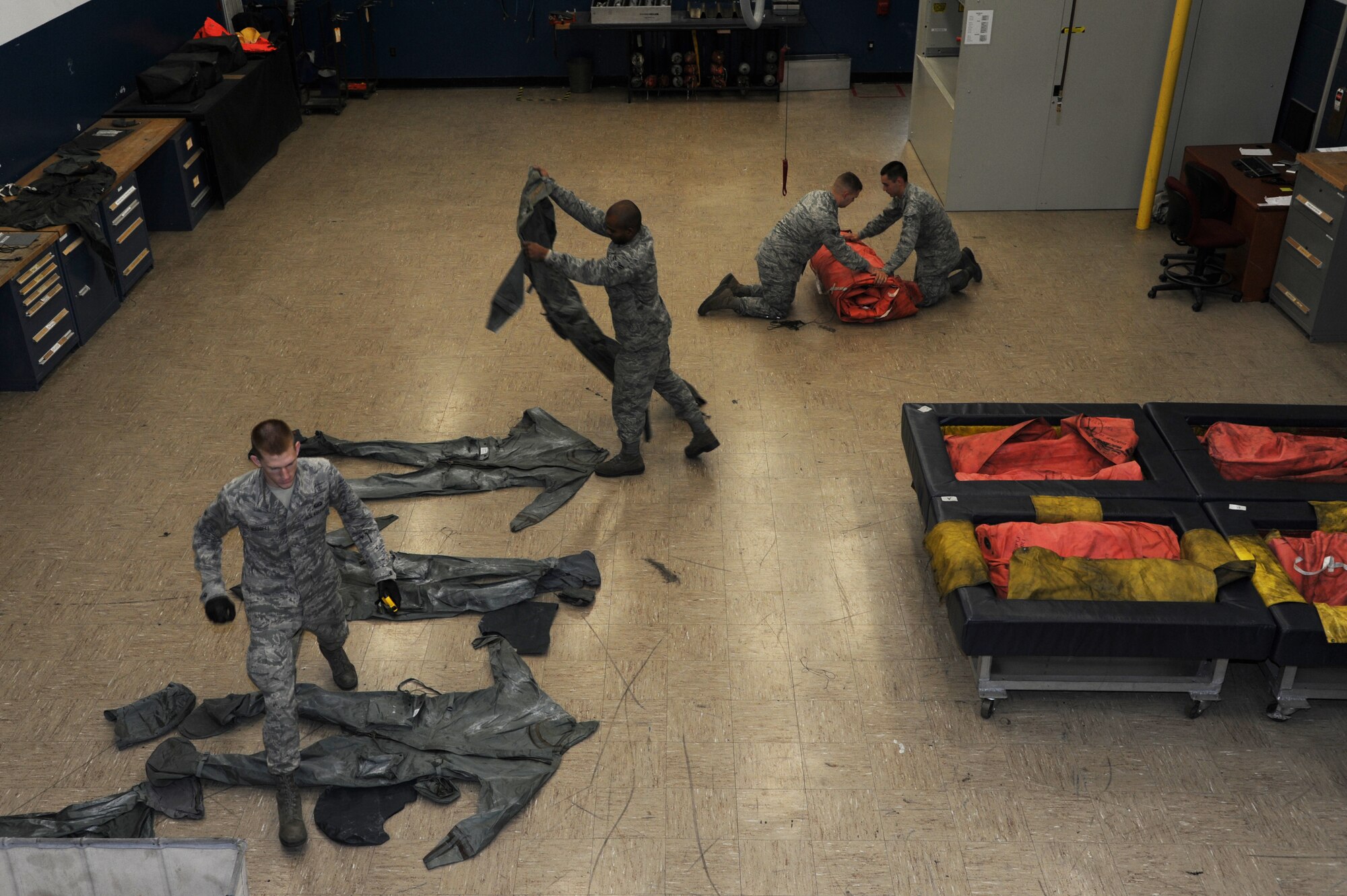 Airmen fold wetsuits and an inflatable raft Nov. 25, 2014, at Little Rock Air Force Base, Ark. Airmen who work in the floatation section of aircrew flight equipment are responsible for maintaining floatation devices and stocking survival kits on inflatable boats. (U.S. Air Force photo by Airman 1st Class Mercedes Muro)