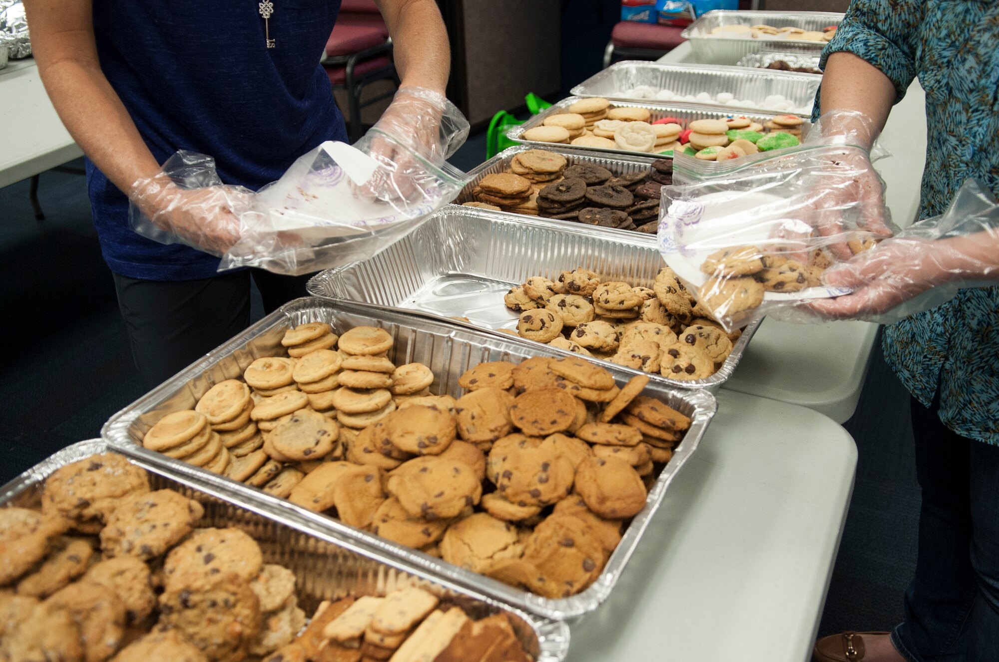 A group of base leadership spouses seals bags of cookies during the Airmen Cookie Drive Dec. 4, 2014, at Moody Air Force Base, Ga. Team Moody surpassed its goal of donating 1,000 cookies by tenfold. (U.S. Air Force photo by Senior Airman Marrero/Released)
