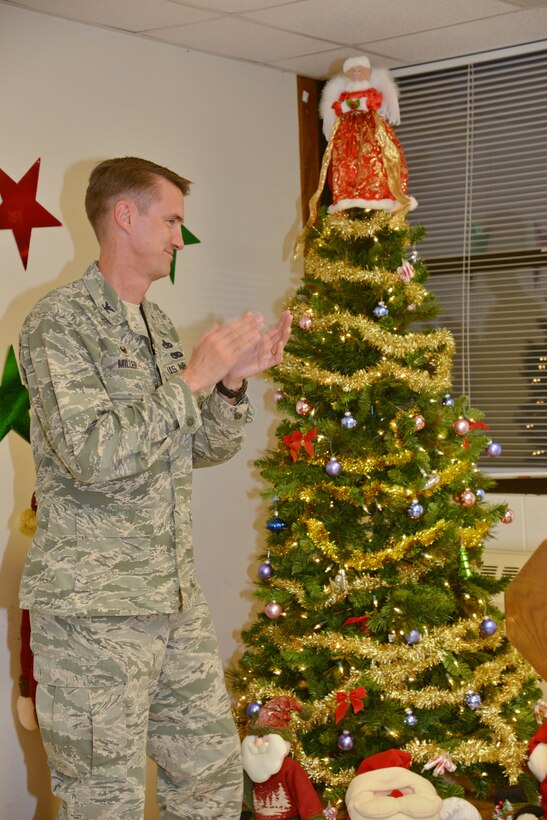 Col. Tom Miller, 377th Air Base Wing commander, lights the holiday tree at the annual Tree Lighting Ceremony at the Base Chapel Dec. 4. All planned festivities were moved inside the chapel due to rainy weather. (Photo by Jamie Burnett)