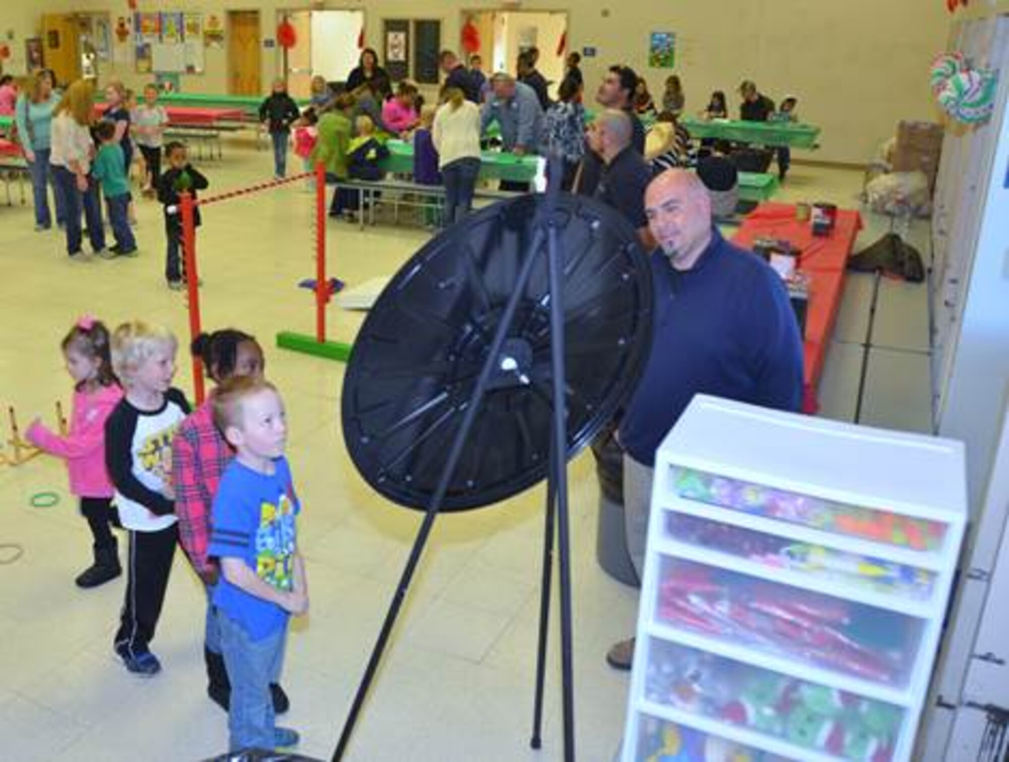 Tomas Fabela (right) and military children watch the prize wheel spin at the 2nd annual Tis the Season. Corvias Military Living sponsored the event and game away hundreds of prizes to include gift cards, toys, crafts and food. (Courtesy photo by Mark Nettles)