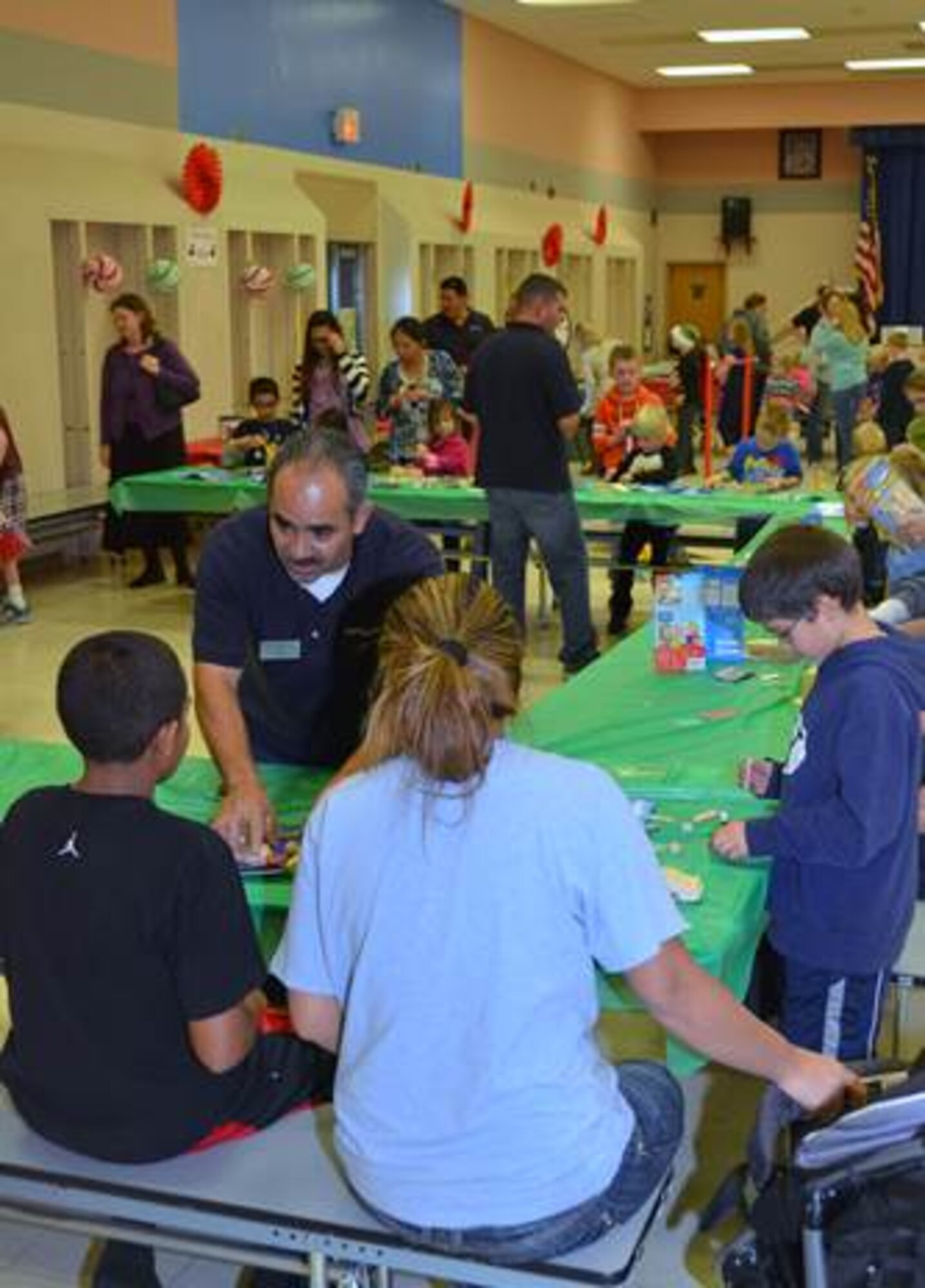 Corvias team member Juan Perez (left) helped an Edwards AFB teen put together a wooden toy at the Tis the Season event Dec. 4 at Branch Elementary.  Military children hammered together 300 wooden toys at the event; the toys, food, crafts and prizes were provided free of charge by Corvias Military Living. (Courtesy photo by Mark Nettles)