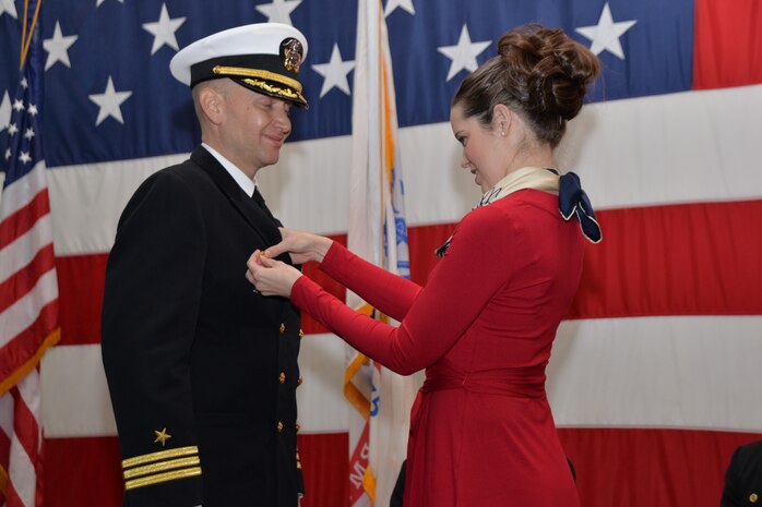 Elizabeth Cole pins the command pin on her husband, Cmdr. Joseph Cole, during the Naval Consolidated Brig Charleston change of command ceremony Dec. 5, 2014, onboard the USS Yorktown in Mt. Pleasant, S.C.  Cole assumed command from Cmdr. Patrick Boyce who will be reporting to USS Ronald Reagan (CVN 76) as the operations officer. (U.S. Air Force photo/Eric Sesit)