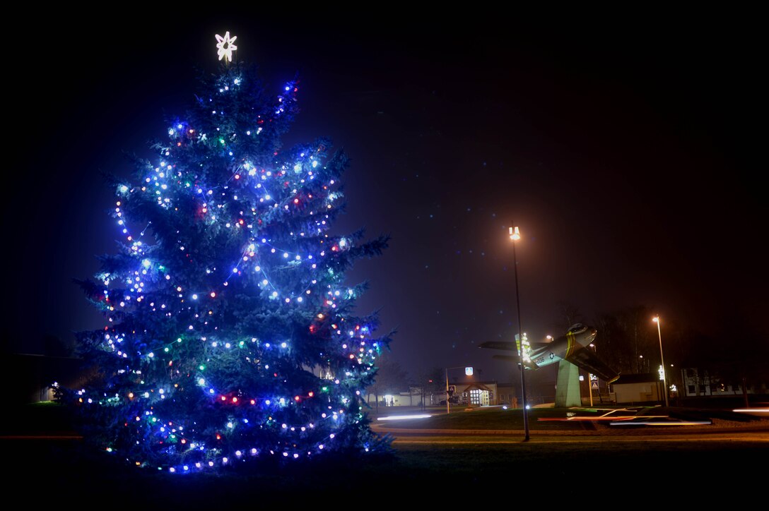 A decorated evergreen tree stands illuminated at the Saber Circle on Spangdahlem Air Base, Germany, Dec. 4, 2014. U.S. Air Force Col. Pete Bilodeau, 52nd Fighter Wing commander, and family members of deployed service members threw the light switch. (U.S. Air Force photo by Airman 1st Class Timothy Kim/Released)