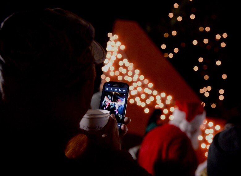 An Airman takes a photo of Santa Claus interacting with the community during the annual tree-lighting ceremony at the Eifel Lanes Bowling Center on Spangdahlem Air Base, Germany, Dec. 4, 2014. Family members and children crowded around Santa Claus to take photos and ask for their Christmas wishes. (U.S. Air Force photo by Airman 1st Class Timothy Kim/Released)