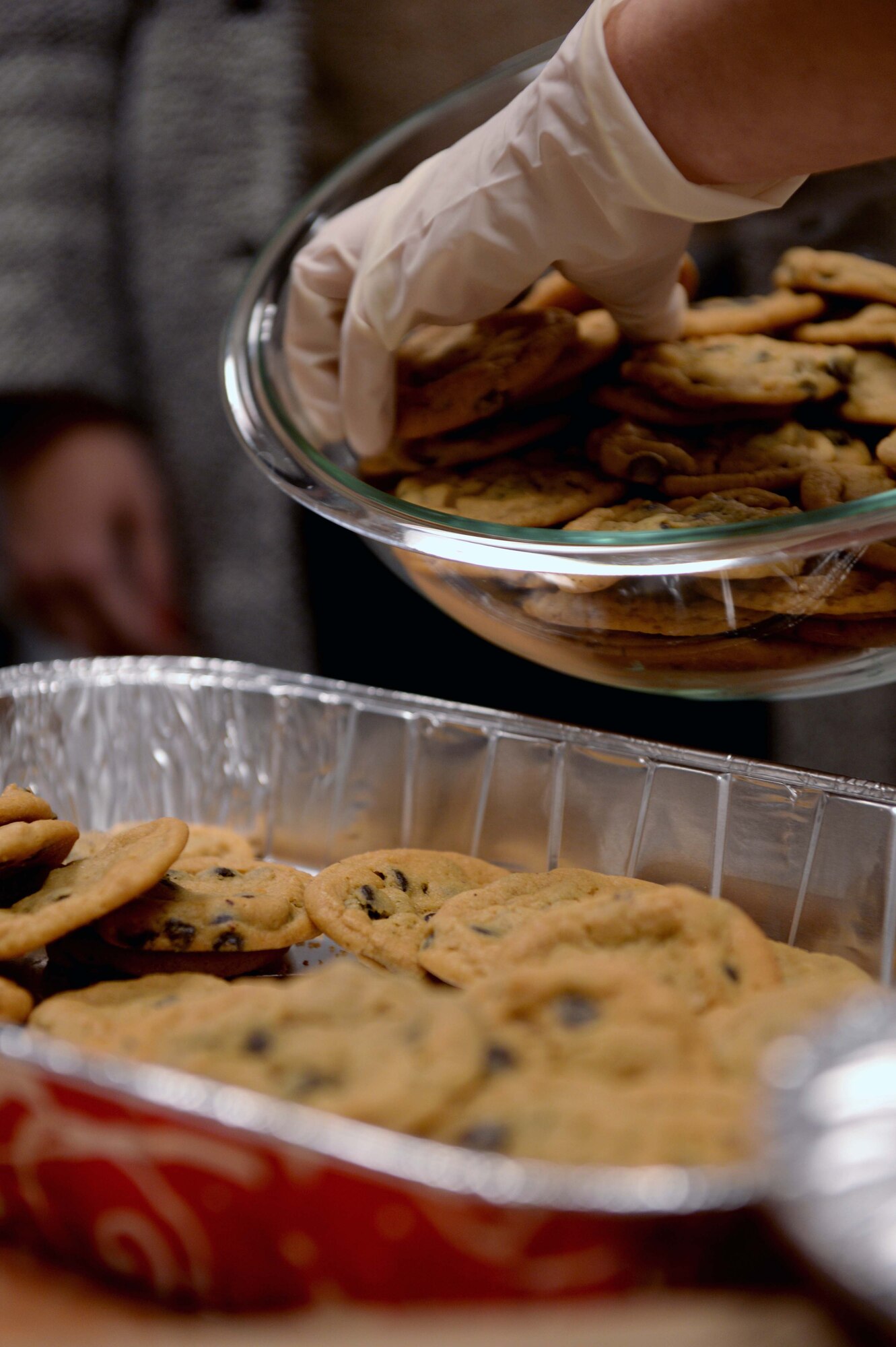 A volunteer places donated cookies into an aluminum bin at the Airman & Family Readiness Center at Spangdahlem Air Base, Germany, Dec. 4, 2014. Members of the Spangdahlem community baked cookies and donated a total of 800 dozen cookies for the drive. (U.S. Air Force photo by Airman 1st Class Timothy Kim/Released)