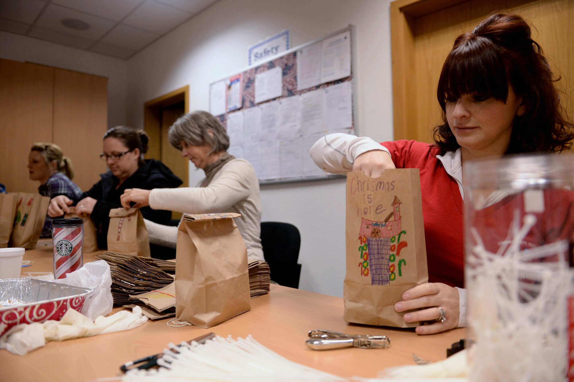 Volunteers fill bags of cookies at the Airman & Family Readiness Center at Spangdahlem Air Base, Germany, Dec. 4, 2014. Volunteers from Spangdahlem Spouses & Enlisted Members Club, Officers’ and Civilians’ Spouses Club and the Spangdahlem community offered to help package cookies for Airmen residing in the base dormitories. (U.S. Air Force photo by Airman 1st Class Timothy Kim/Released)