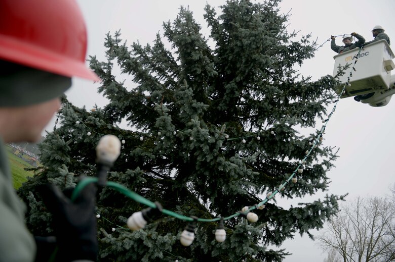 U.S. Air Force Airmen from the 52nd Civil Engineer Squadron Airmen decorate an evergreen tree at the Saber Circle in Spangdahlem Air Base, Germany, Dec. 2, 2014. Airmen used an electrical bucket truck to put the lights near the top of the tree. (U.S. Air Force photo by Airman 1st Class Timothy Kim/Released)