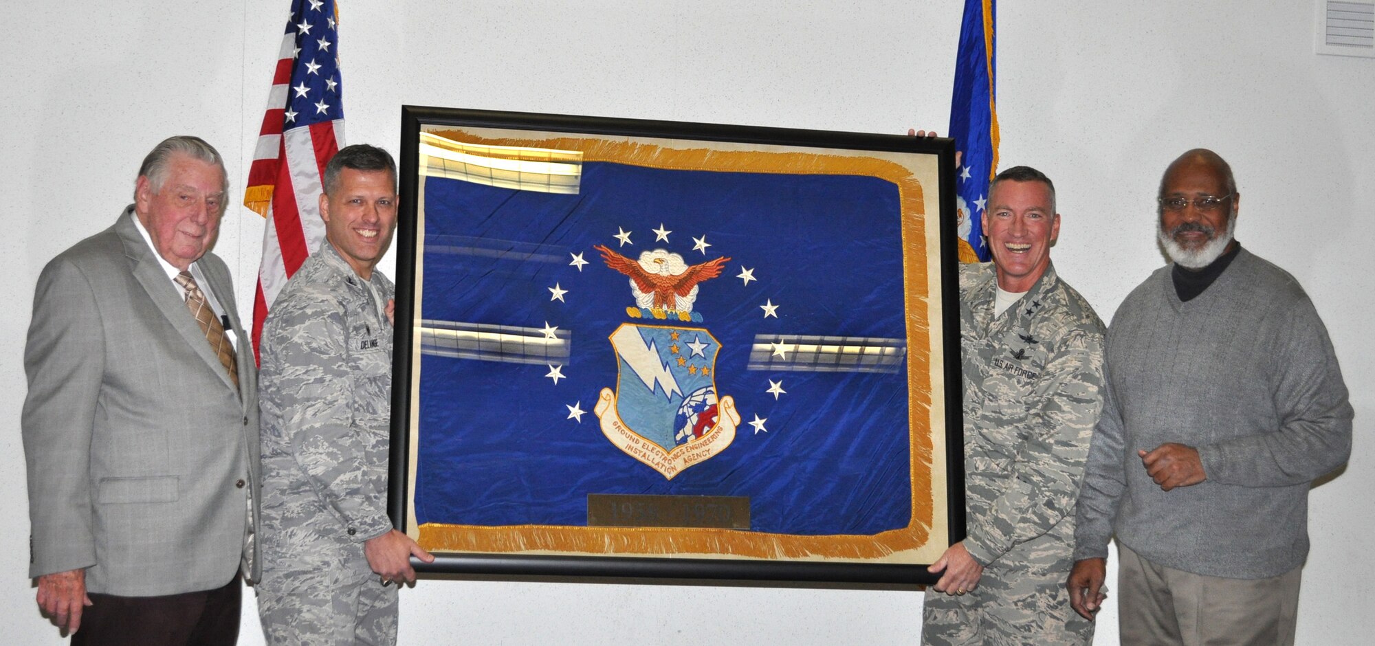 From left, retired Chief Master Sgt. James Street, 38th Cyberspace Engineering Installation Group Commander Col. Eric DeLange, 24th Air Force Commander Maj. Gen. Edwin Wilson and retired Chief Master Sgt. William Riley display the official Ground Electronics Engineering Installation Agency flag during a ceremony Nov. 13. The flag now has a permanent home in Bldg. 4064. (Air Force photo by April McDonald)