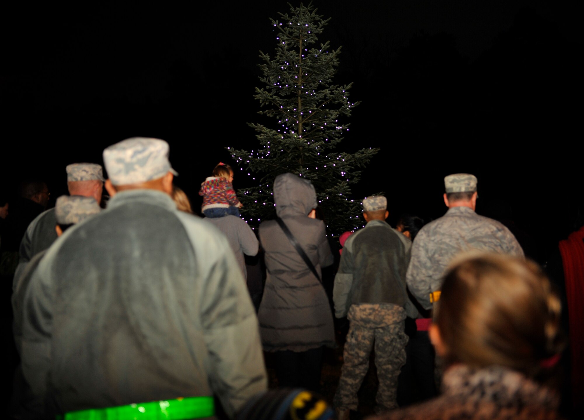 Civilians, military members and families gather around the tree and sing carols during the tree lighting ceremony, Dec. 1, 2014 at Ramstein Air Base, Germany. The event consisted of musical performances, the tree lighting ceremony, a meet-and-greet with Santa and cookies and hot cocoa. (U.S. Air Force photo/Airman 1st Class Larissa Greatwood)