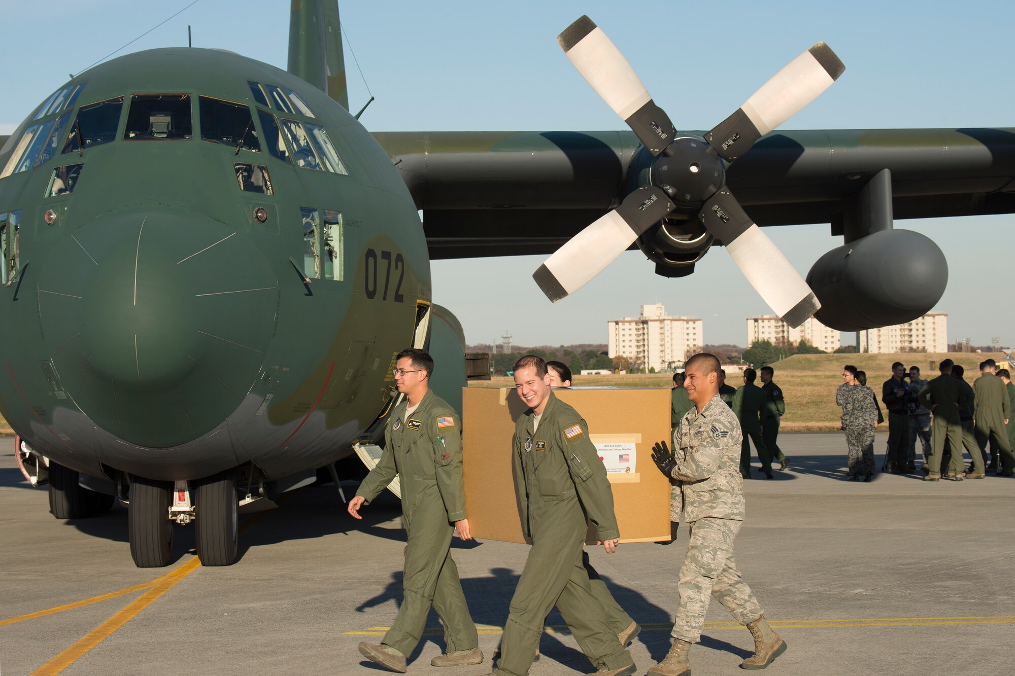 Members from the 36th Airlift Squadron carry a donation box from Japan Air Self-Defense Force Komaki Air Base, Dec. 3, 2014, at Yokota Air Base, Japan. JASDF members from the 401st Squadron delivered Operation Christmas Drop donations as part of 40 tons of humanitarian aid headed to various austere locations throughout the Pacific. (U.S. Air Force photo by Osakabe Yasuo/Released)