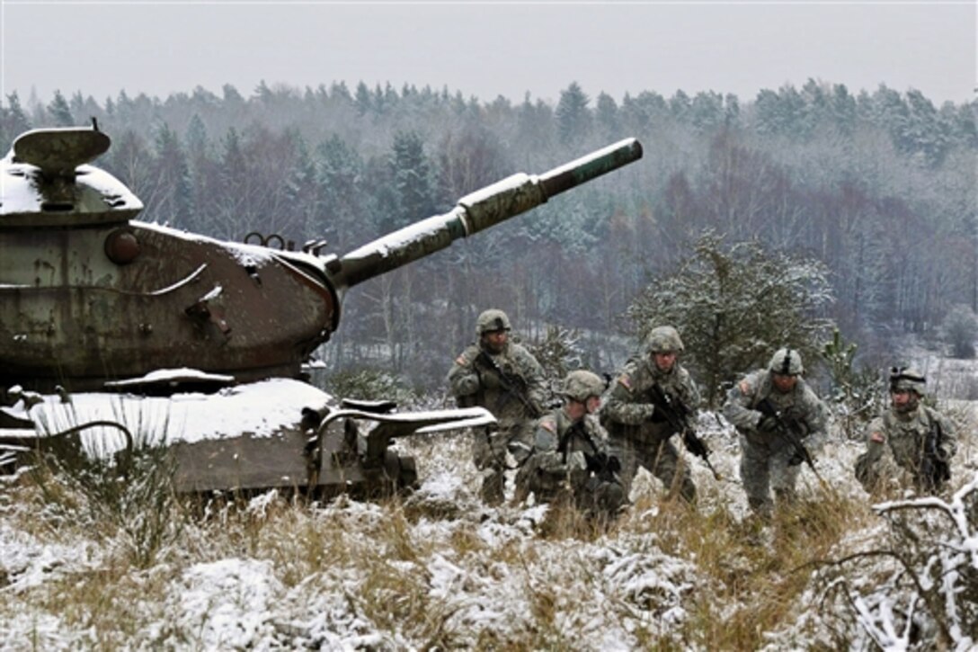U.S. soldiers move from behind an old tank during an exercise at Hohenfels Training Area, Germany, Dec. 3, 2014. 