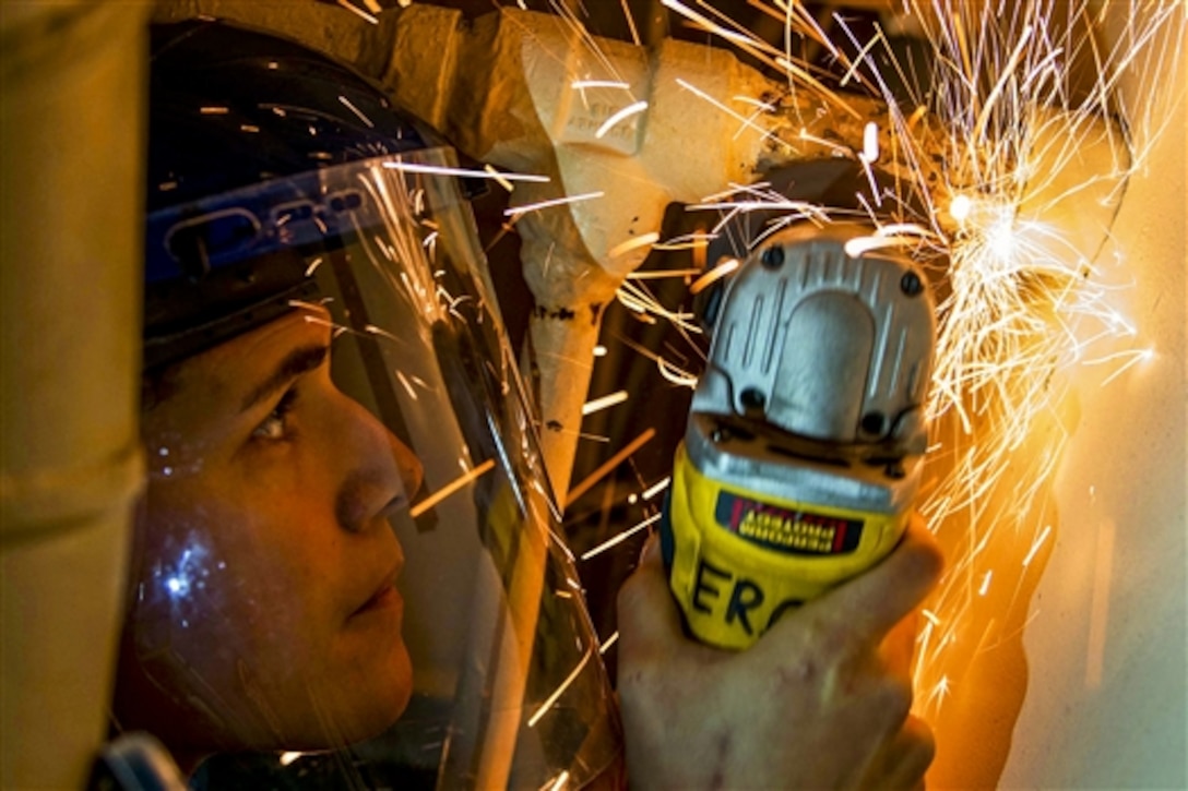 Navy Petty Officer 3rd Class Maya Gengenbacher grinds a weld on a pipe on the aircraft carrier USS John C. Stennis in Bremerton, Wash., Nov. 25, 2014.