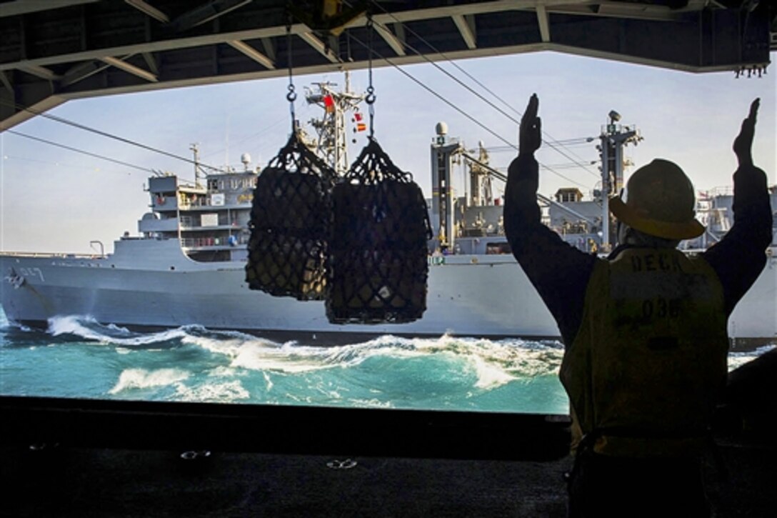 U.S. Navy Petty Officer 2nd Class Kevin Cotton directs cargo into the hangar bay of the aircraft carrier USS Carl Vinson during a replenishment-at-sea operation with ship USNS Rainier in the Arabian Gulf,  Dec. 3, 2014.