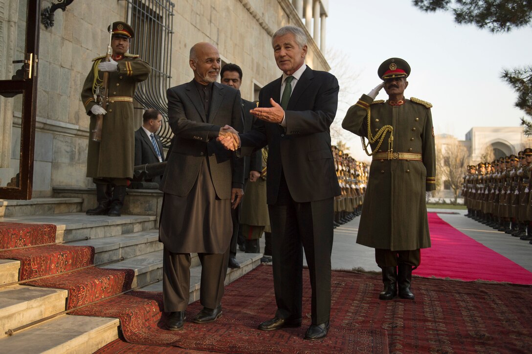 U.S. Defense Secretary Chuck Hagel, left, speaks with Afghan President Ashraf Ghani during an honor cordon at the Presidential Palace in Kabul, Afghanistan, Dec. 6, 2014.
