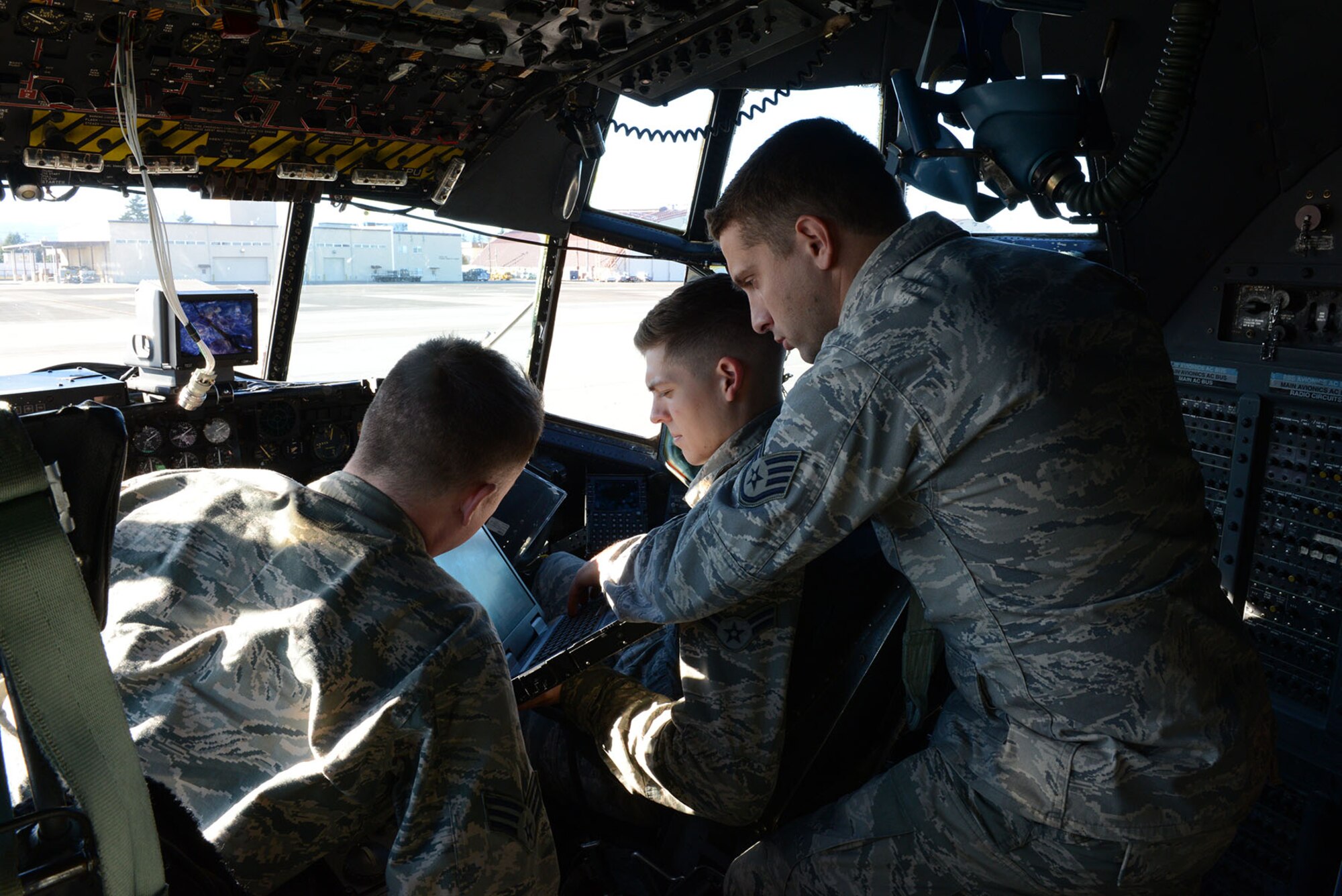 Staff Sgt. Austin Carracino, 374th Aircraft Maintenance Squadron instruments and flight control systems craftsman, right, looks up a technical order for a C-130 Hercules with Senior Airman Trey Massey and Airman 1st Class Andrew Hamilton Dec. 2, 2014, at Yokota Air Base, Japan. Technical orders, commonly referred to as TOs, provide maintainers with the information needed to properly repair the aircraft.  (U.S. Air Force photo by Senior Airman Desiree Economides/Released)