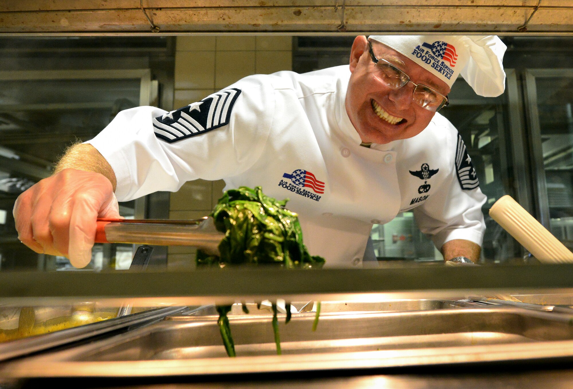 Chief Master Sgt. Tom Mason, the 919th Special Operations Wing command chief, serves up some greens at the holiday meal at the Duke Field dining facility Dec. 6.  Members of the wing’s leadership took turns serving lunch menu items to the Airmen during the unit training assembly.  (U.S. Air Force photo/Tech. Sgt. Cheryl Foster)   