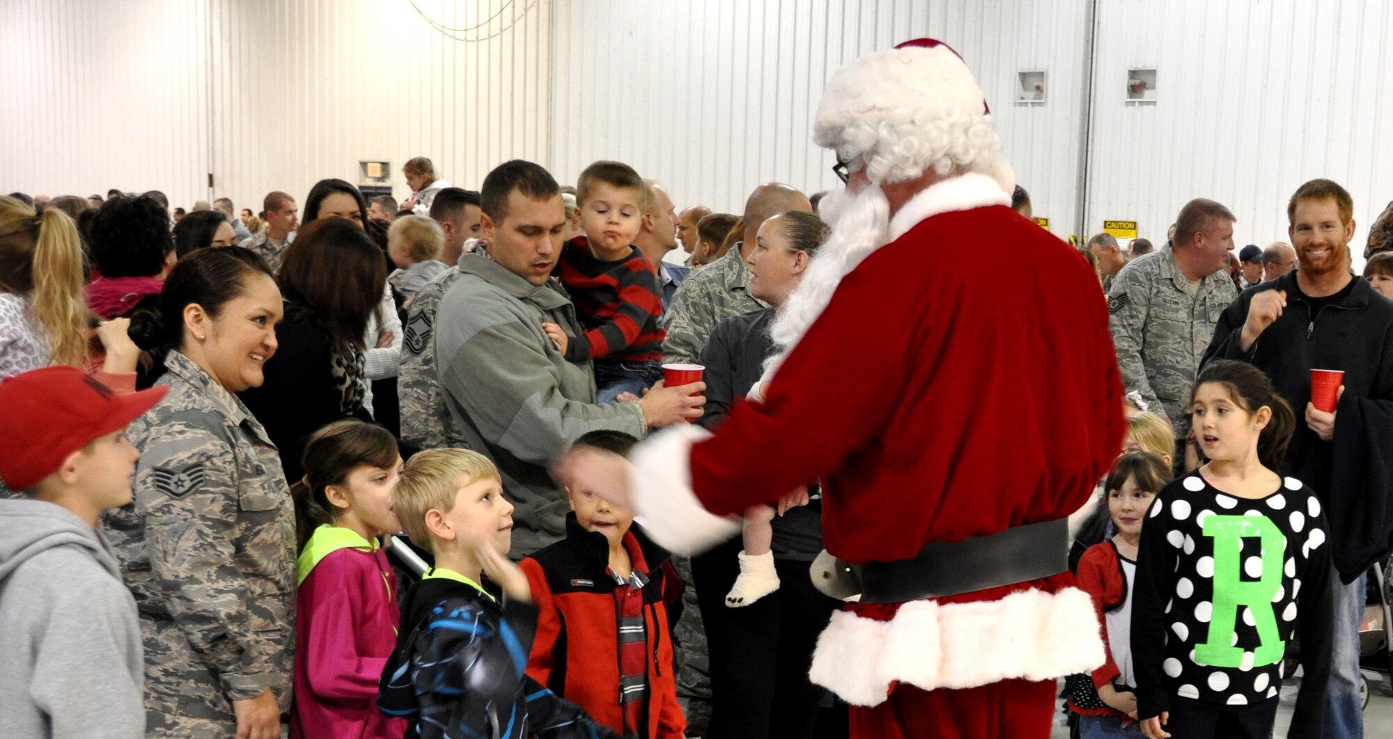 Santa greets members of the 442d Fighter Wing and their children as the hangar doors opened and the  he maked a grand entrance to the Christmas party December 6 at Whiteman AFB, Mo.  Santa met with an unprecedented number of children, about 300, during the Christmas party. (Photo by Missouri Civil Air Patrol)