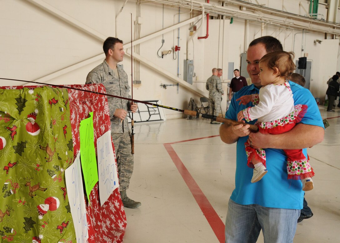 U.S. Air Force Senior Airman Matthew Thomas and his daughter, Syndey-Grace, play a fishing game during the 186th Air Refueling Wing Family Day celebration on Key Field National Guard Base, Meridian, Miss., Dec. 6, 2014. Airmen and their families fellowshipped and enjoyed food and games. (U.S. Air National Guard photo by Senior Airman Jessica Fielder/Released)