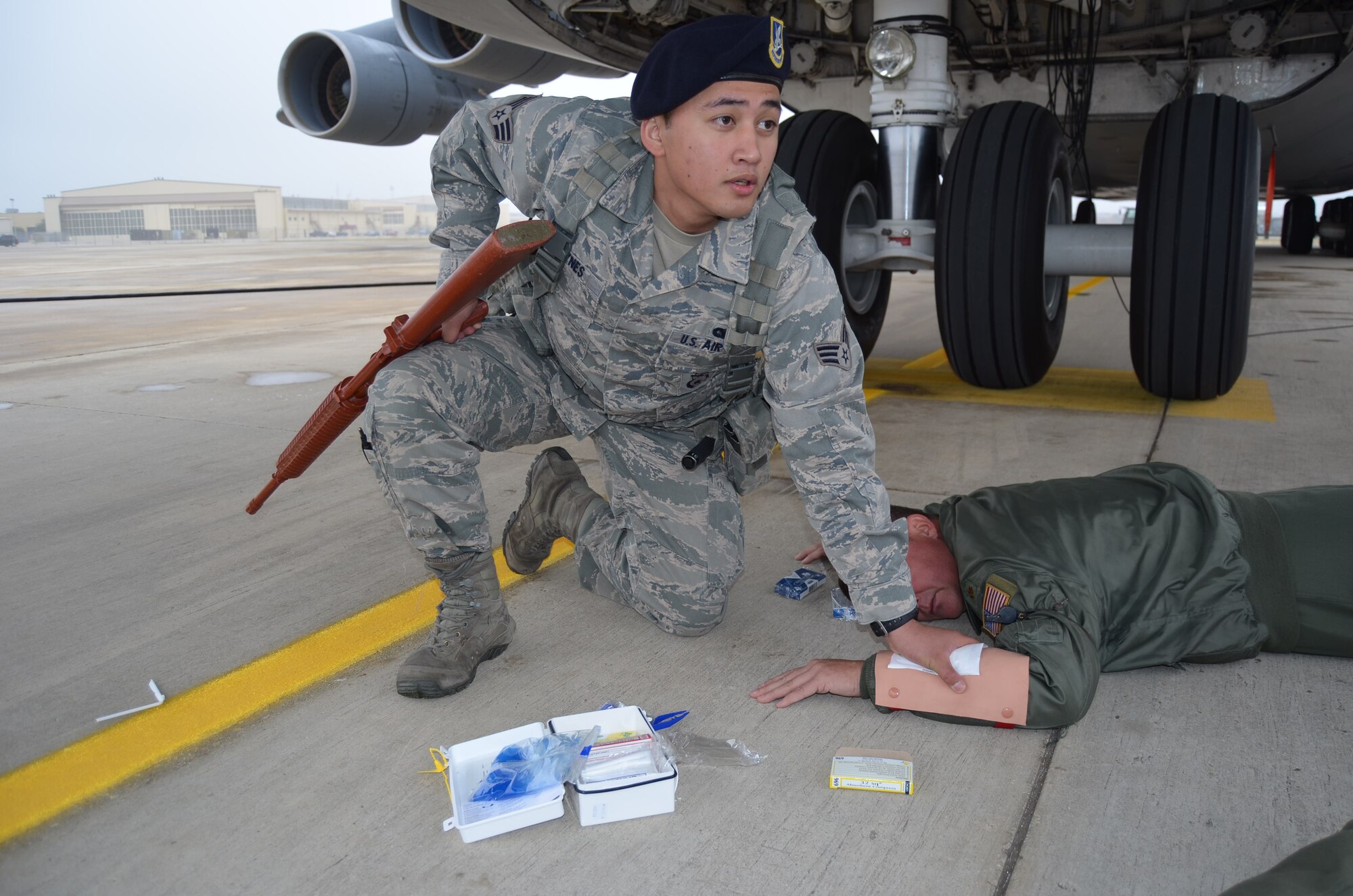 Senior Airman Michael Raynes, 802nd Security Forces Squadron, renders first aid to Maj. Anthony Lytle, 68th Airlift Squadron, during the anti-hijacking exercise held Dec. 5, 2014 on Joint Base San Antonio-Lackland, Texas. (U.S. Air Force Photo/ Maj. Tim Wade)