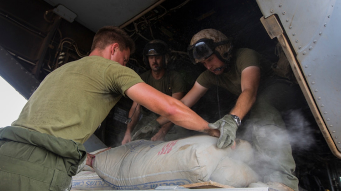 U.S. Marines with SPMAGTF Crisis Response - Africa load bags of concrete, that will be used by local and international health organizations to build Ebola Treatment Units, into an MV-22B Osprey during Operation United Assistance in Monrovia, Liberia, Nov. 21, 2014. United Assistance is a Department of Defense operation to provide command and control, logistics, training, and engineering support to U.S. Agency for International Development- led efforts to contain the Ebola virus outbreak in West African nations. (U.S. Marine Corps photo by Lance Cpl. Andre Dakis/ SPMAGTF-CR-AF Combat Camera/Released)
