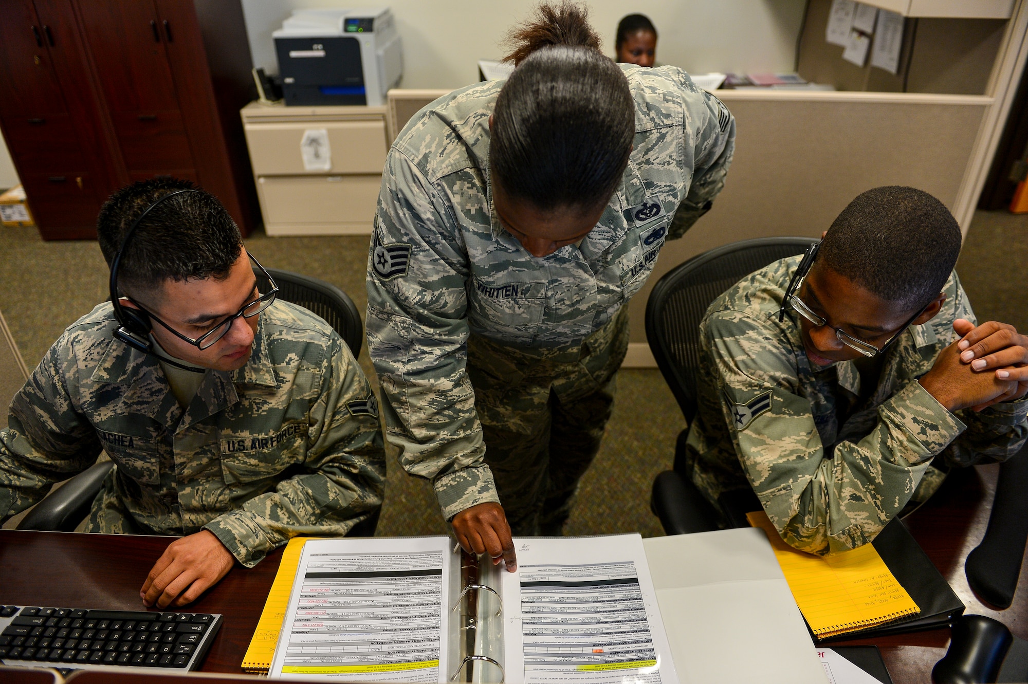 Staff Sgt. Konisha Whitten, 1st Special Operations Civil Engineer Squadron operations management, reviews completed work orders with Airman 1st Class Joseph Olachea and Airman 1st Class Charles Flowers, 1st SOCES civil engineer journeyman at the “Fish Bowl”, Hurlburt Field, Fla., Oct. 17, 2014. Airmen at the Fish Bowl take calls and create work orders for various shops at the 1st SOCES to complete around the base. (U.S. Air Force photo/Airman 1st Class Jeff Parkinson)