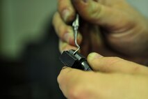 Senior Airman Christopher Crawley, 1st Special Operations Security Forces Squadron Combat Arms Training and Maintenance instructor, cleans carbon from an M9 pistol part at Hurlburt Field, Fla., December 2, 2014. CATM instructors provide firing training and maintain all weapons used by CATM and Security Forces. (U.S. Air Force photo/Airman 1st Class Jeff Parkinson)