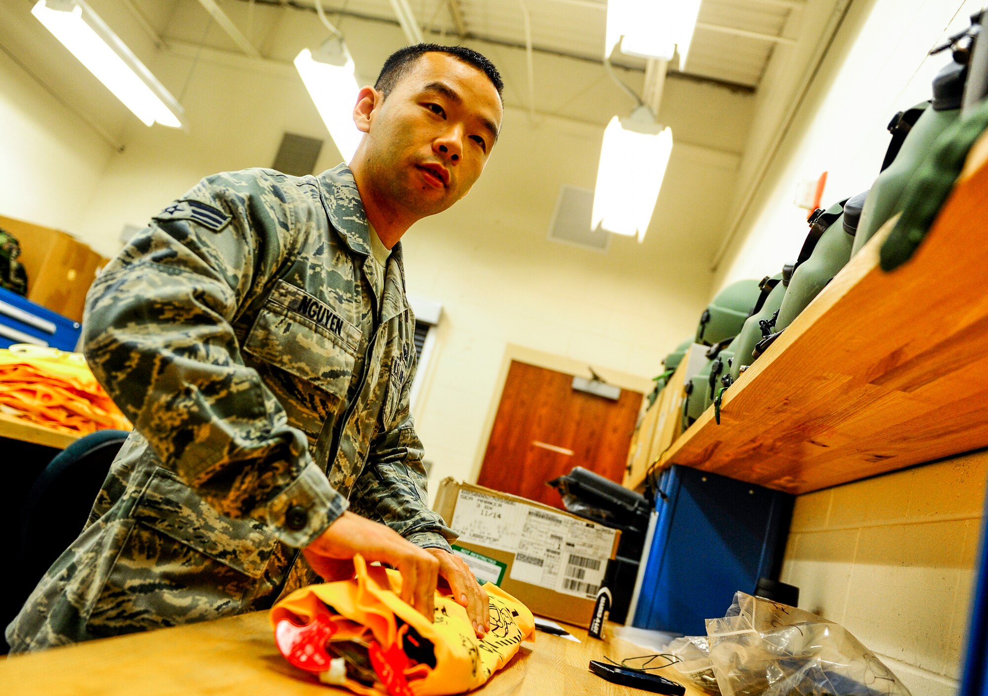 Senior Airman Cuong Nguyen, a 1st Special Operations Support Squadron aircrew flight equipment journeyman, folds a life preserver unit at Hurlburt Field, Fla., Dec. 4, 2014. Nguyen works at the 8th Special Operations Squadron Air Crew Flight Equipment office. (U.S. Air Force photo/Senior Airman Christopher Callaway)