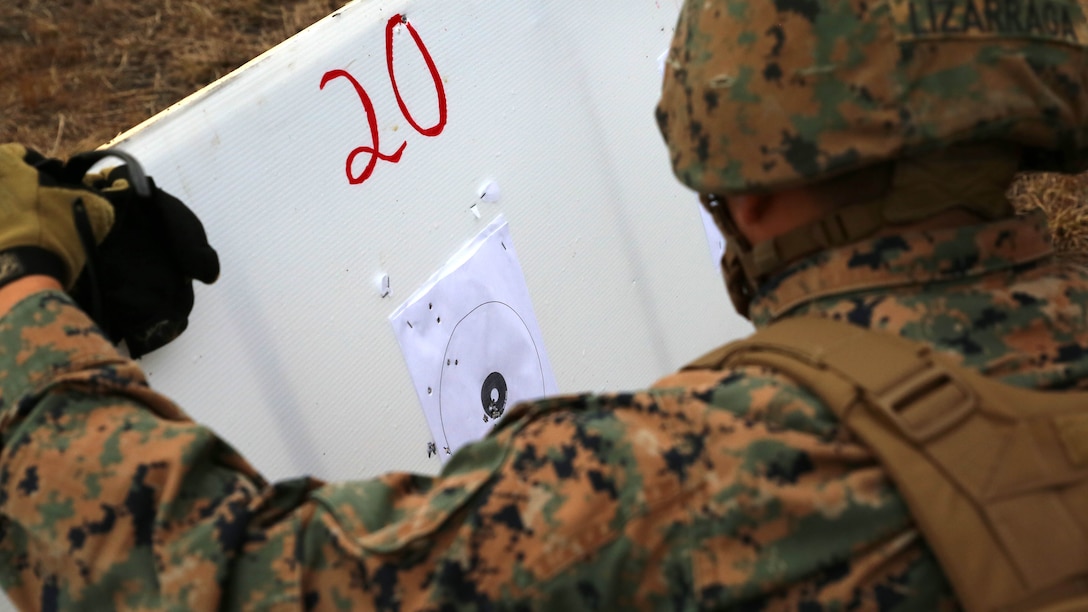 Cpl. Steve Lizarraga, rifleman, 1st Platoon, Company A, Ground Combat Element Integrated Task Force, examines the initial shot groups of Lance Cpl. Anne Creasy, rifleman, 2nd Platoon, Co. A, GCEITF, during the M27 Infantry Automatic Rifle 100-meter zeroing course of fire during a three-day field exercise at the Verona Loop training area on Marine Corps Base Camp Lejeune, North Carolina, Dec. 3, 2014. 