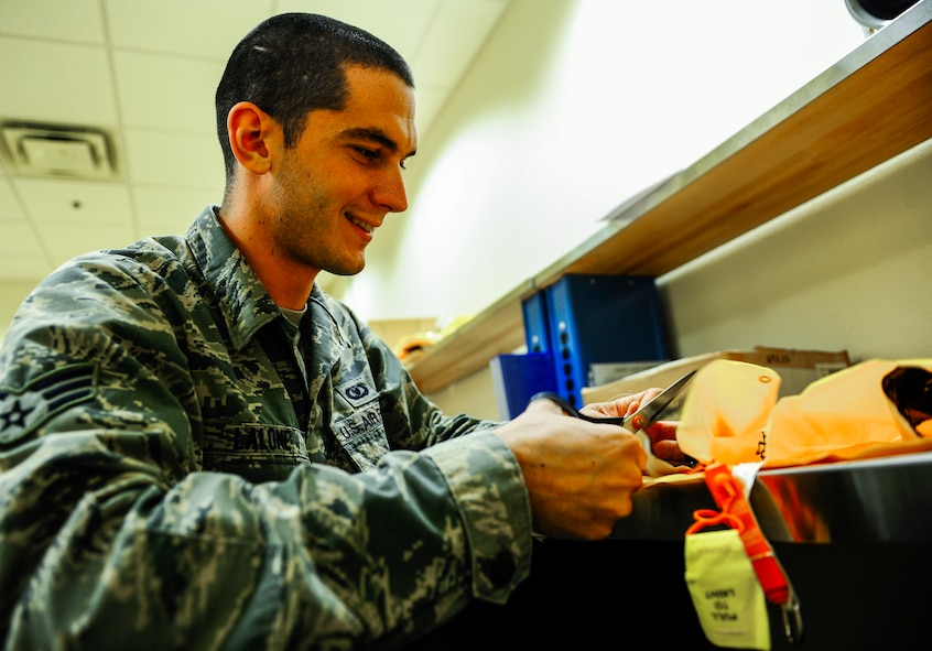 Senior Airman Glen Lalone, a 1st Special Operations Support Squadron flight equipment journeyman, cuts a string off a new life preserver unit at Hurlburt Field, Fla., Dec. 4, 2014. Lalone is part of a crew that works in the 8th Special Operations Squadron Air Crew Flight Equipment office. (U.S. Air Force photo/Senior Airman Christopher Callaway) 