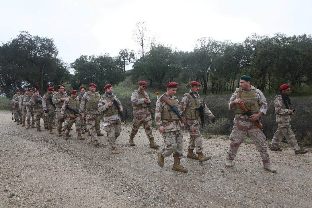 Role-players participating in a simulated bi-lateral training exercise with U.S. Marines walk in formation during a Realistic Urban Training exercise aboard Fort Hunter Ligget, Calif., Dec. 6, 2014.  RUT prepares the 15th Marine Expeditionary Unit's Marines for their upcoming deployment, enhancing their combat skills in environments similar to those they may find in future missions. (U.S. Marine Corps Photo by Sgt. Jamean Berry/Released)