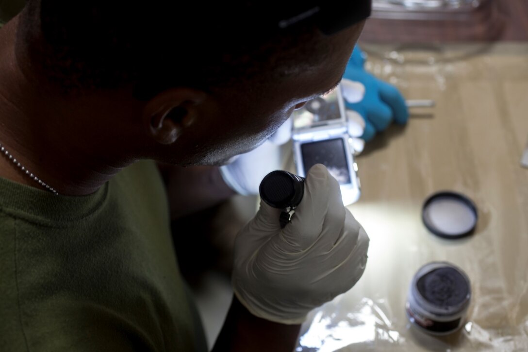 U.S. Marine Lance Cpl. Shaquille Tidwell looks at evidence for fingerprints during realistic urban training aboard Fort Hunter Liggett, Calif., Dec. 6, 2014. Tidwell is a military policeman with the Law Enforcement Detachment, Combat Logistics Battalion 15, 15th Marine Expeditionary Unit. RUT prepares the 15th MEU Marines for their upcoming deployment, enhancing their combat skills in environments similar to those they may find in future missions. (U.S. Marine Corps photo by Cpl. Elize McKelvey/Released)