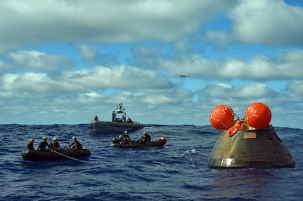 PACIFIC OCEAN (Dec. 5, 2014) - Sailors from the amphibious transport dock ship USS Anchorage (LPD 23) and Navy divers assigned to Explosive Ordnance Disposal Mobile Unit (EODMU) 11, Mobile Dive and Salvage Company 11-7, attach a line to the Orion crew module. Anchorage is conducting the first exploration test flight for the NASA Orion Program. EFT-1 is the fifth at sea testing of the Orion Crew Module using a Navy well deck recovery method.  141205-N-FO359-385