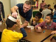 Col. Ronald Braney, from Stafford, Virginia, places an American Indian hat on a child’s head Nov. 23 during the second annual Thanksgiving celebration with Tai Chu En Children’s Home at the Camp Kinser Chapel. The event began with the children assembling paper hats as the Marines, sailors and spouses assisted them. Following the crafts, the children and volunteers sat down for a Thanksgiving feast including turkey, corn and pumpkin pie. Braney is the commanding officer for Combat Logistics Regiment 35, 3rd Marine Logistics Group, III Marine Expeditionary Force. (U.S. Marine Corps photo by Lance Cpl. Rebecca Elmy/Released)