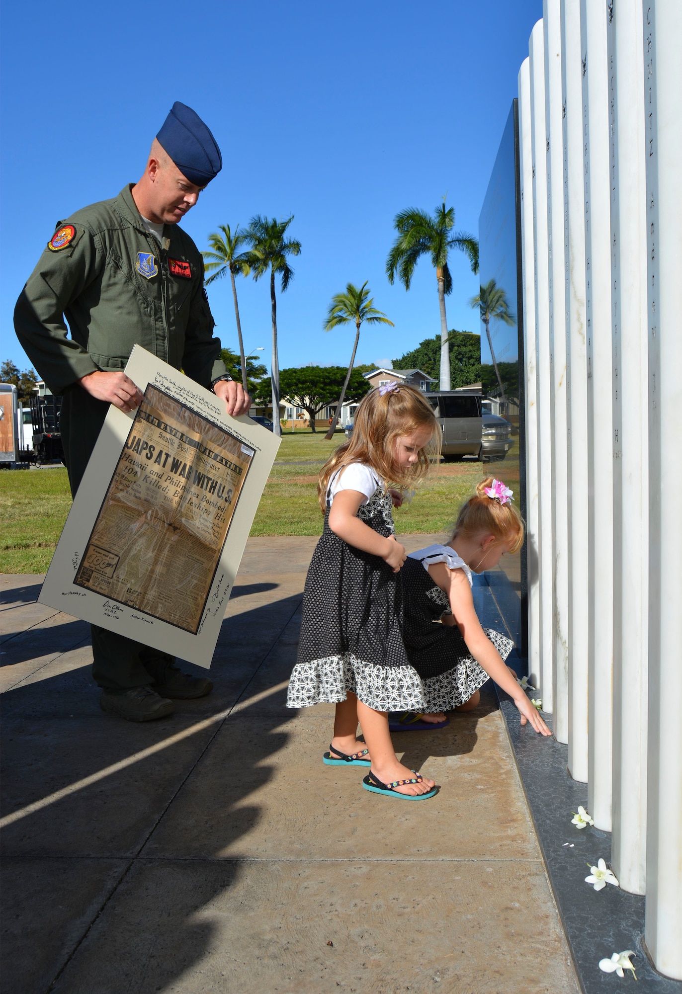 Air Force Staff Sgt. Christopher Bankston, from the 535th Air Lift Squadron, and his daughters honor fallen sailors at the USS Oklahoma Memorial by placing orchids at the base of marble name stones following the National Park Service annual USS Oklahoma Memorial ceremony, at Pearl Harbor, Dec. 7, 2014. This year's theme focused on "Preserving the Memory." (U.S. Navy photo by Mass Communication Specialist 1st Class Katherine Hofman/Released)

