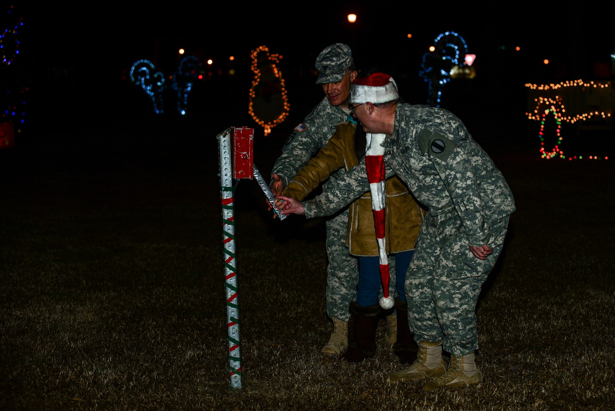 U.S. Army Maj. Gen. Ross Ridge, U.S. Army Initial Military Training Center of Excellence deputy commanding general, and Col. William Galbraith, 733rd Mission Support Group commander, joins Grace Hong, daughter of Army Sgt. David Hong, Fort Eustis chaplain assistant, as they light the Christmas tree at Fort Eustis, Va., Dec. 5, 2014. The 59th tree lighting ceremony was held at Seay Plaza. (U.S. Air Force photo by Senior Airman Kimberly Nagle/Released)