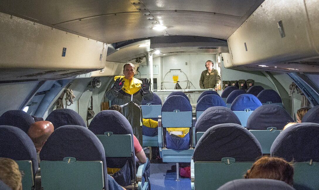 TRAVIS AIR FORCE BASE, Calif. --Tech. Sgt. Richard Bline (left), loadmaster, demonstrates operation of the inflatable life jacket, as  Master Sgt. Adam Goldsberry, loadmaster, reads the passenger safety brief in the troop compartment of a C-5B Galaxy about to depart Aug. 14, 2014, from Yokota Air Base, Japan. The troop compartment of the upper deck of the cargo aircraft includes accommodations for 73 passengers in rear-facing seats. The two aviators from the 312th Airlift Squadron, Travis Air Force Base, Calif., were flying a channel mission, moving high-priority cargo and passengers among U.S. bases in the Pacific Command area of responsibility.  (U.S. Air Force photo/Lt. Col. Robert Couse-Baker)
