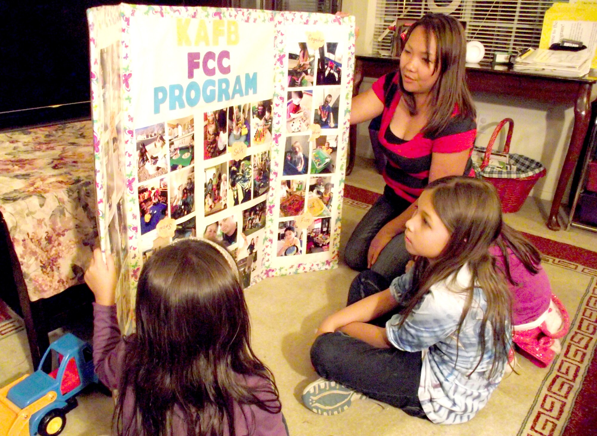 Marie Stabe, 2014 Air Force Materiel Command Family Child Care Provider of the Year, shows a picture board to some of the children she cares for. Stabe was lauded as an FCC provider who has completed a thorough battery of training, inspections and certification to be licensed, and has gone above and beyond. (Photo by Jim Fisher). 
