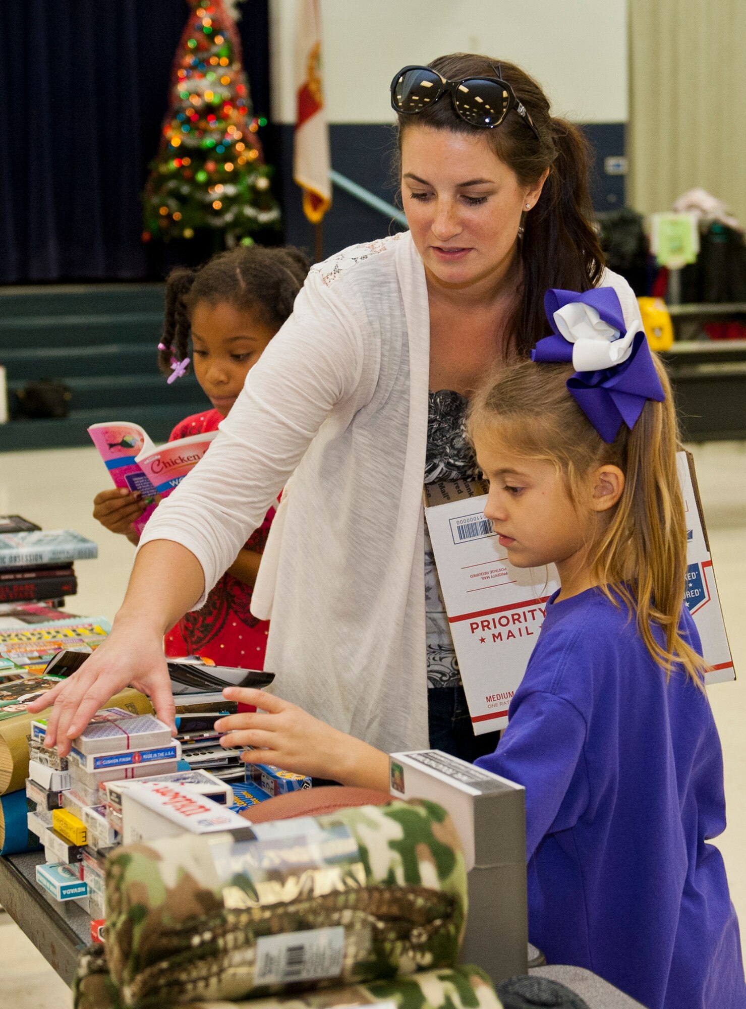 Eglin spouse, Cassie Harley and her daughter, Kylie accompanied by her friend, Nia Crawford select items for their package at the Eglin Elementary School cafeteria during the troop care drive Dec. 5. The CGOC collected 2,500 cards, letters and drawings from local schools and the Red Cross. These cards, letters and drawings were included in the care packages along with books, coffee, magazines, snacks and various comfort items. The items were donated by various community businesses and organizations, and the CGOC, who also hosted the event. Volunteers packed a total of 92 care packages for Eglin’s deployed. (U.S. Air Force photo/Ilka Cole